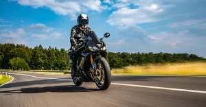 A bike rider is having fun riding his motorcycle on a clear sunny day on an open country road.