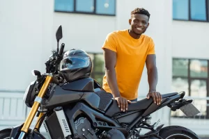 Young man leans on his black motorcycle as he thinks about his loan interest rates